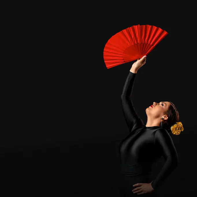 A traditional Spanish flamenco dancer raising a red fan, showcasing the cultural heritage of Spain, part of Shin-Tours luxury tours.